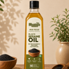 A bottle of Meadow's Organic Black Sesame Oil stands on a wooden table, surrounded by loose sesame seeds in wooden bowls and a potted plant in the background.