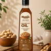 A bottle of Meadow's Organic Ground Nut Oil stands on a wooden table surrounded by peanuts in a bowl and scattered in a scoop, with potted plants in the background.