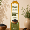 A bottle of Meego's Wood-Pressed Black Sesame Oil stands on a wooden table, surrounded by loose sesame seeds in bowls and a potted plant, with a warm beige background and soft leaf shadows.